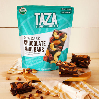 Bag of Chocolate Mini Bars in a bright kitchen setting surrounded by nuts, cranberries, and propped Chocolate Mini Bars.