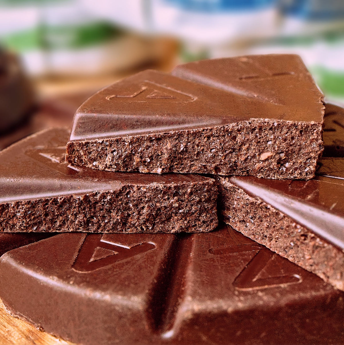 Close up shot of unwrapped and snapped in half chocolate discs, showing the rich stone-ground chocolate texture.