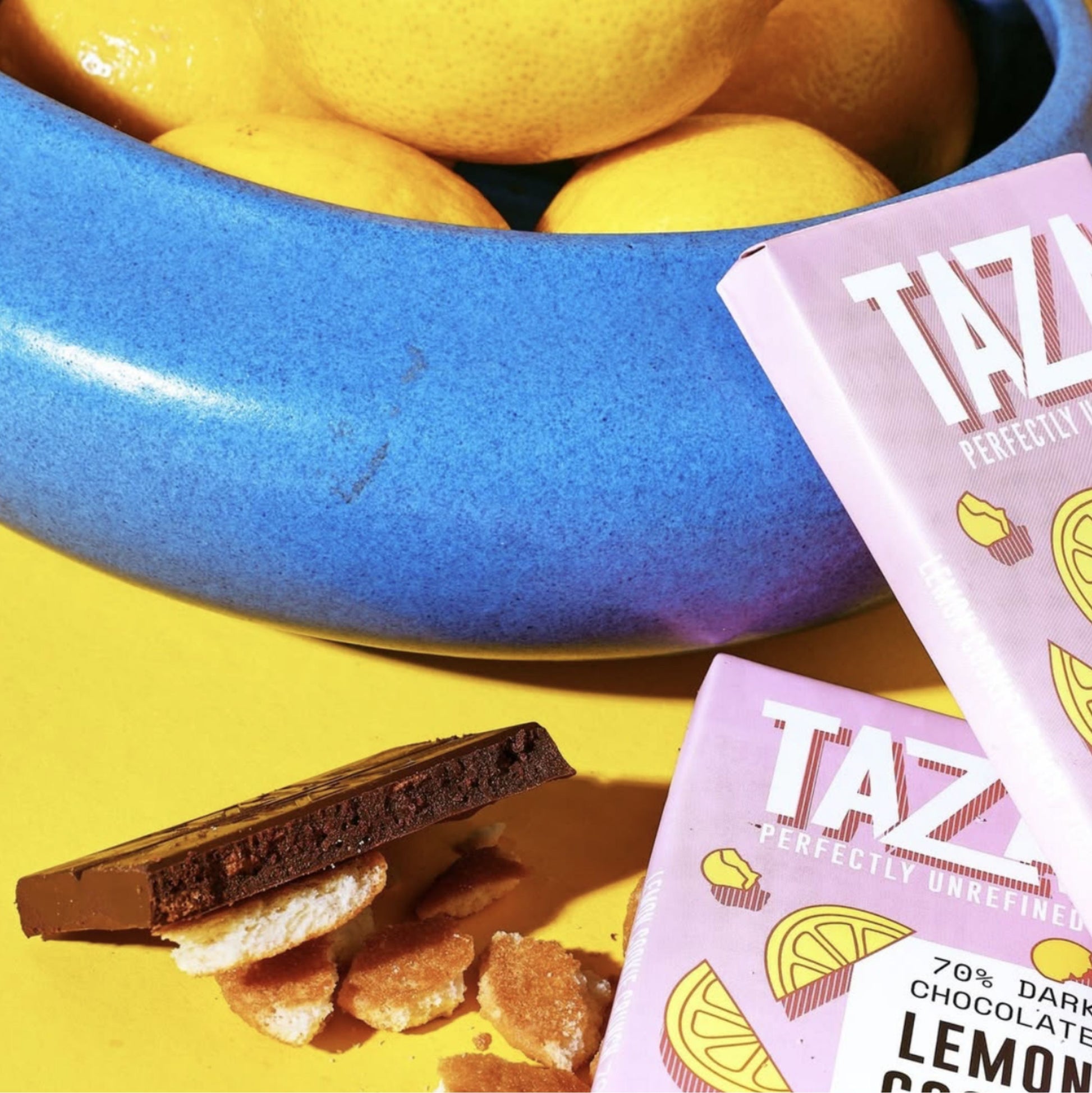 Wrapped and unwrapped Lemon Cookie Crunch Chocolate bars surrounded by lemons and cookie crumbles.
