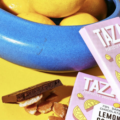 Wrapped and unwrapped Lemon Cookie Crunch Chocolate bars surrounded by lemons and cookie crumbles.