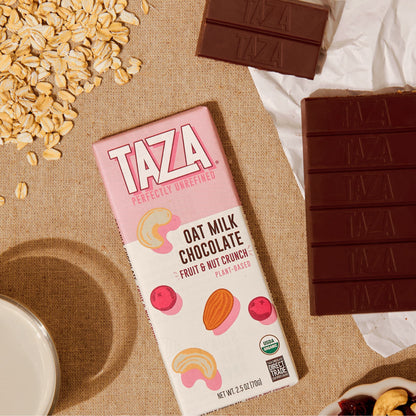 Fruit & Nut Crunch Oat Milk Bar laying next to unwrapped chocolate and oats.