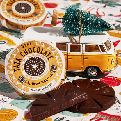 Close up shot of a wrapped and unwrapped Spiked Eggnog Chocolate Disc in a holiday themed place setting.
