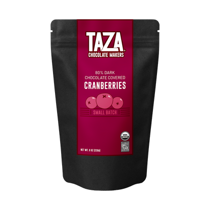 A black stand-up pouch of Taza Chocolate Makers 80% Dark Chocolate Covered Cranberries, featuring a prominent magenta label with white text and illustrations of cranberries.